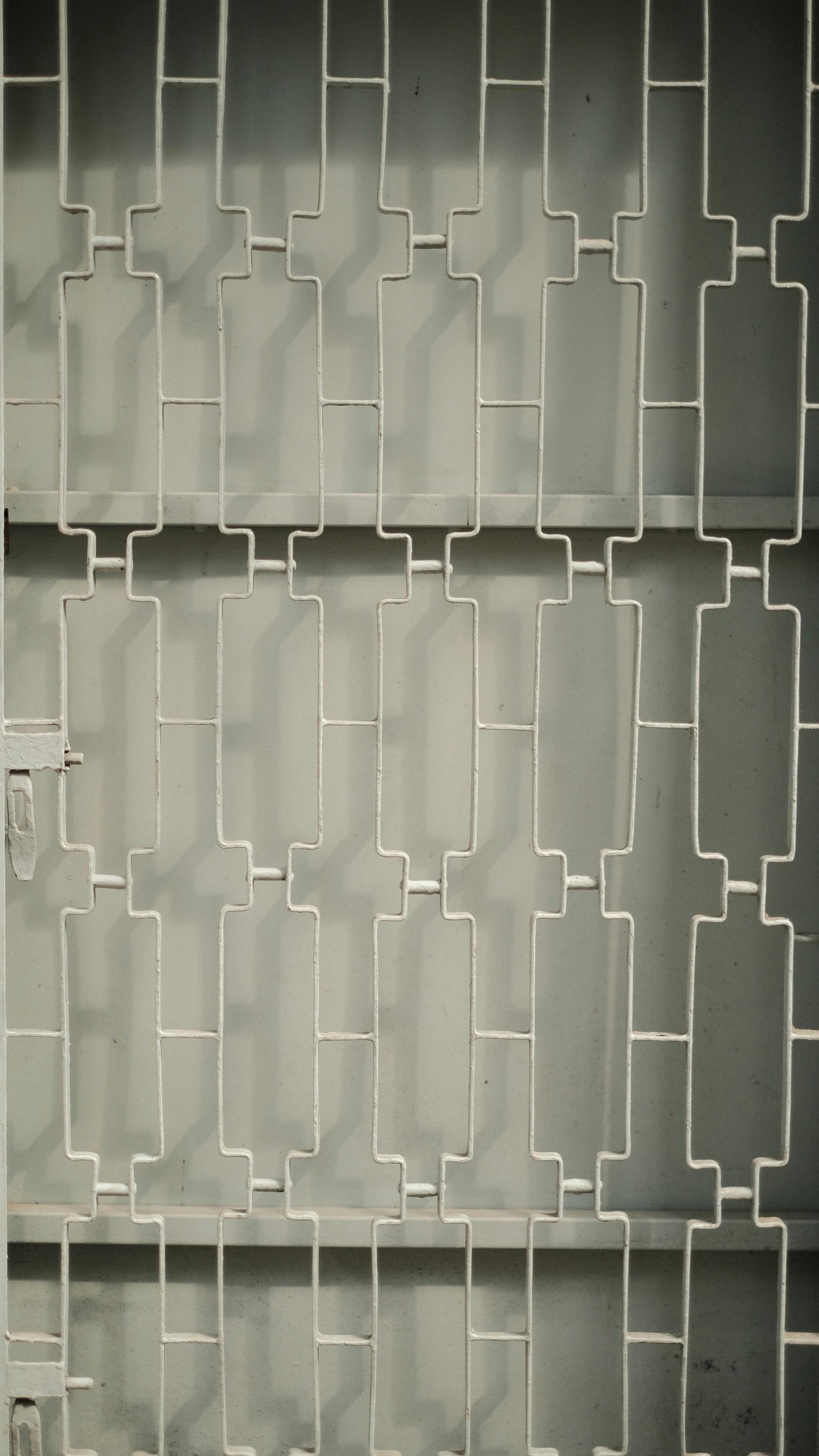 Kostnadsfria Närbild av en vit metallgrind med ett abstrakt geometriskt mönster, som visar upp modern design. Stock foto