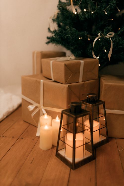 Free Warm and serene festive scene featuring wrapped gifts, glowing candles, and a Christmas tree. Stock Photo