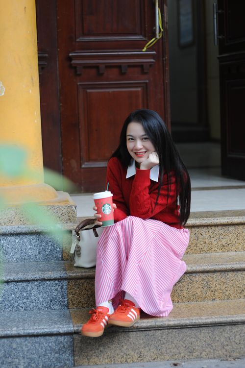 Free Cheerful woman in casual outfit enjoying a coffee on the steps. Stock Photo