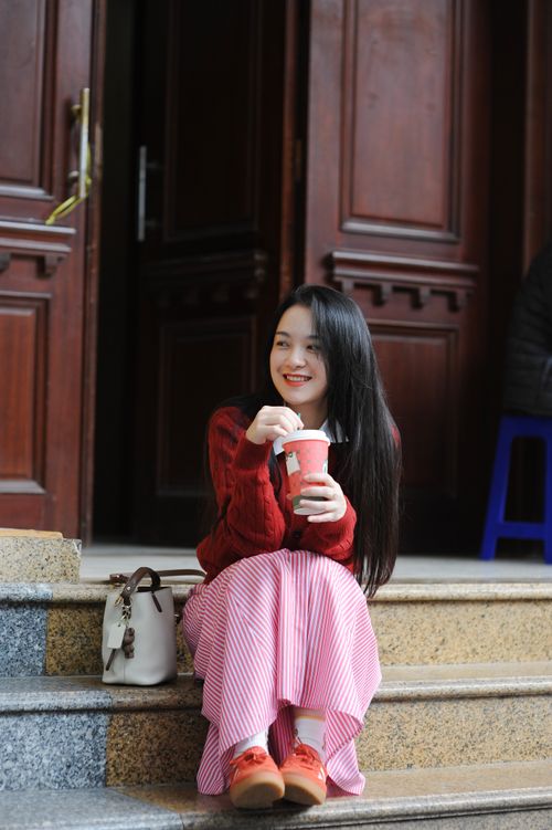 Free Happy woman with coffee sitting on steps outdoors. Casual, relaxed moment. Stock Photo