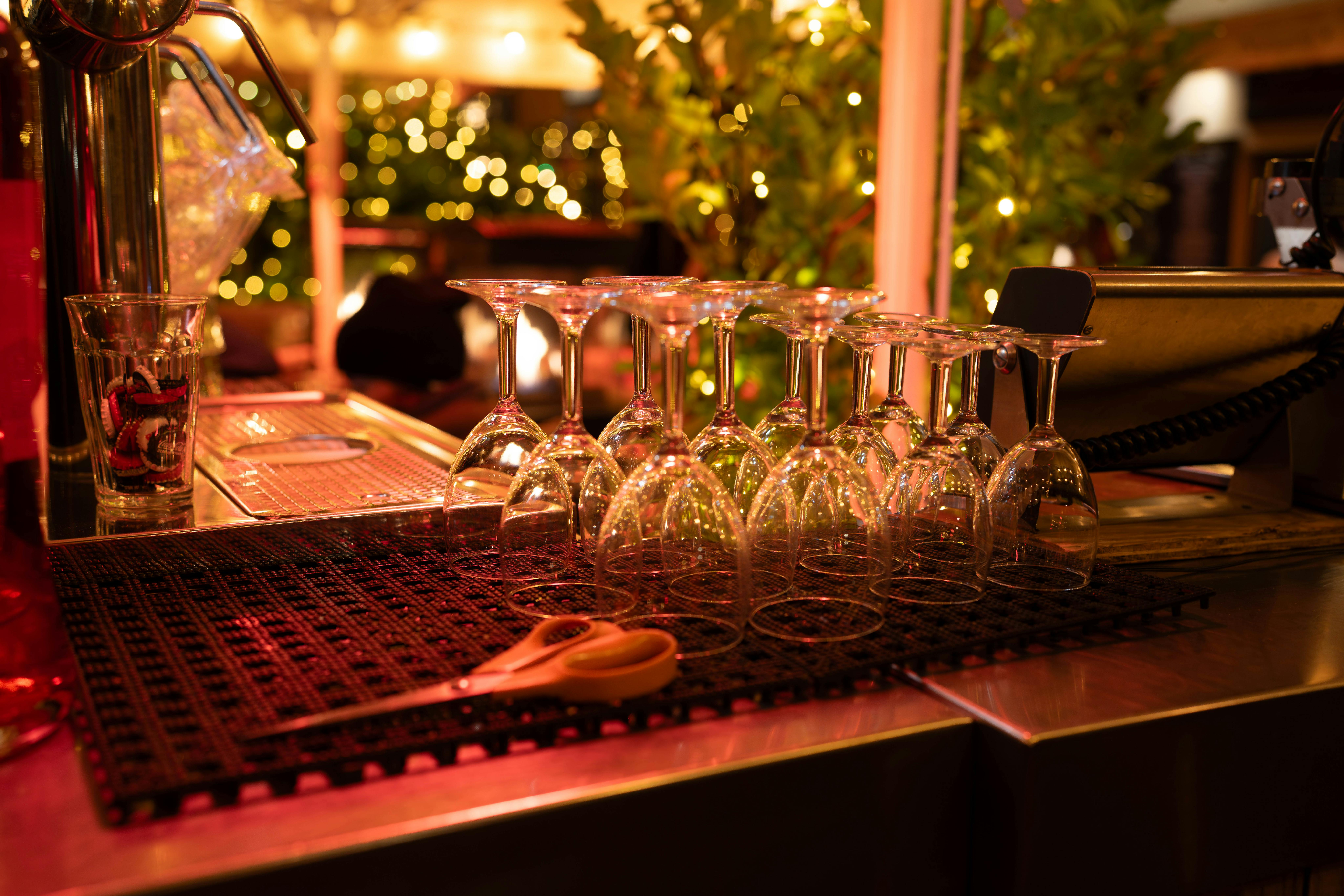 Upside-down wine glasses on a bar counter with warm festive lighting and bokeh.