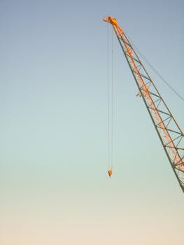 A towering construction crane set against a clear blue sky, signifying strength and industry.