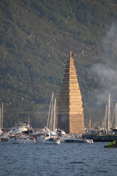 Captivating view of a towering bonfire structure surrounded by boats in Ålesund, Norway.