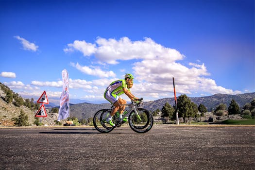 Cyclist in a competitive race on a scenic mountain road with clear skies.