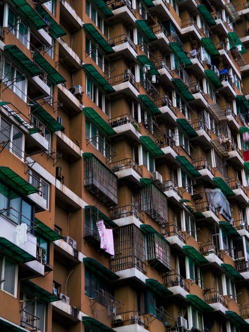 Free Detailed view of an urban apartment building facade featuring rows of balconies with various awnings. Stock Photo