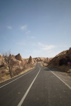 A deserted road stretches through a rocky desert under a clear blue sky.