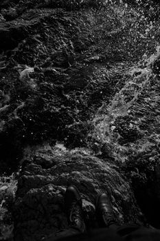 A striking black and white image of a rocky cliffside above a turbulent ocean.