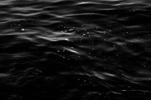Free Captivating black and white image of ocean water surface with reflections and textures. Stock Photo