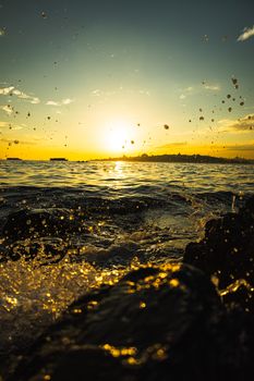 Captivating sunset with splashing waves against rocks, offering a serene and vibrant ocean view.