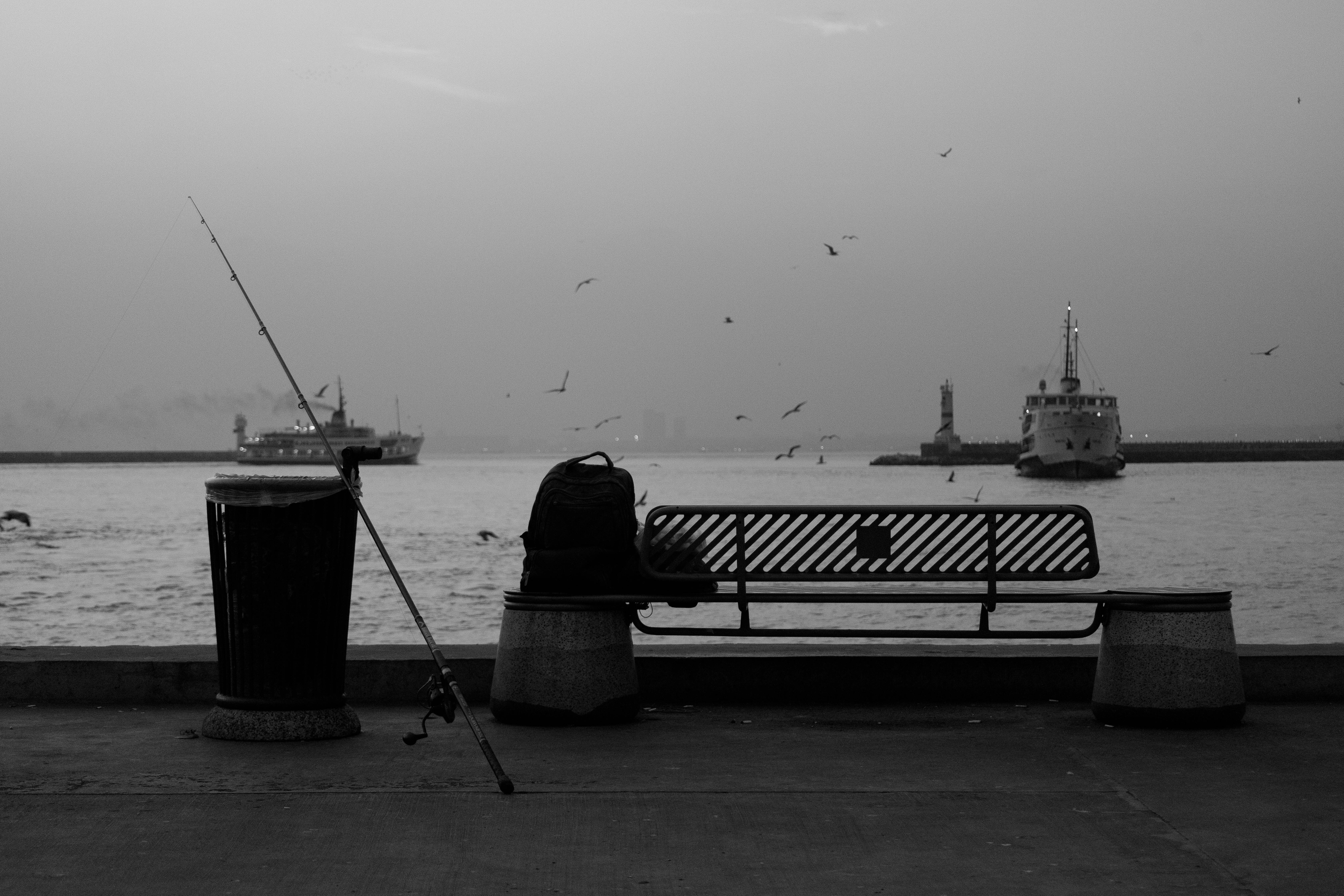 Gratuit Malul apei liniștit, cu o undiță, o bancă și bărci, surprinzând un moment de liniște. Fotografie de stoc