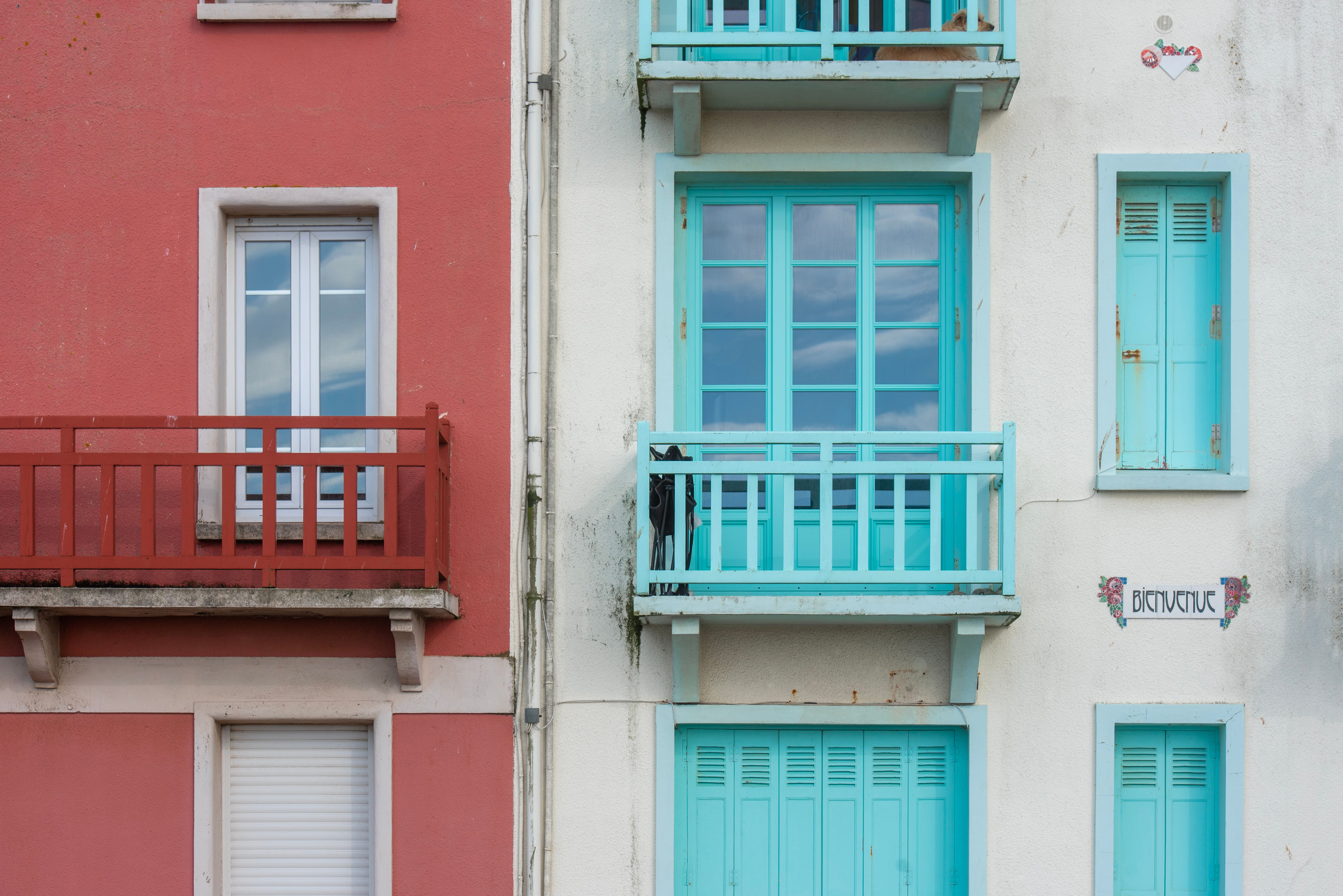 Façades rouge et bleue éclatantes avec balcons, illustrant le design architectural urbain.