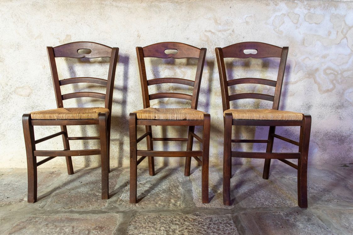 Rustic Wooden Chairs Against Textured Wall · Free Stock Photo