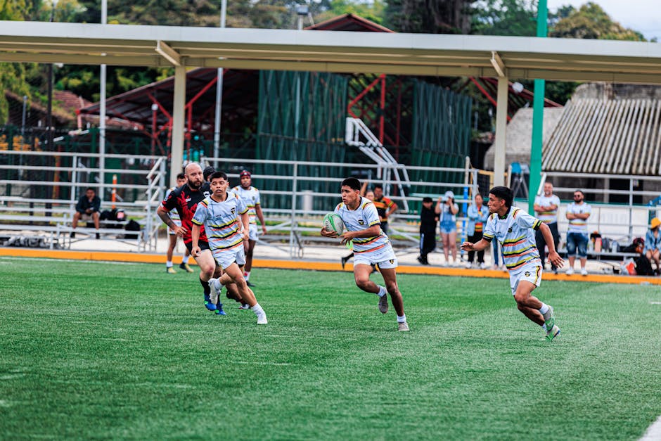 Young men playing an intense rugby match outdoors on a green field.