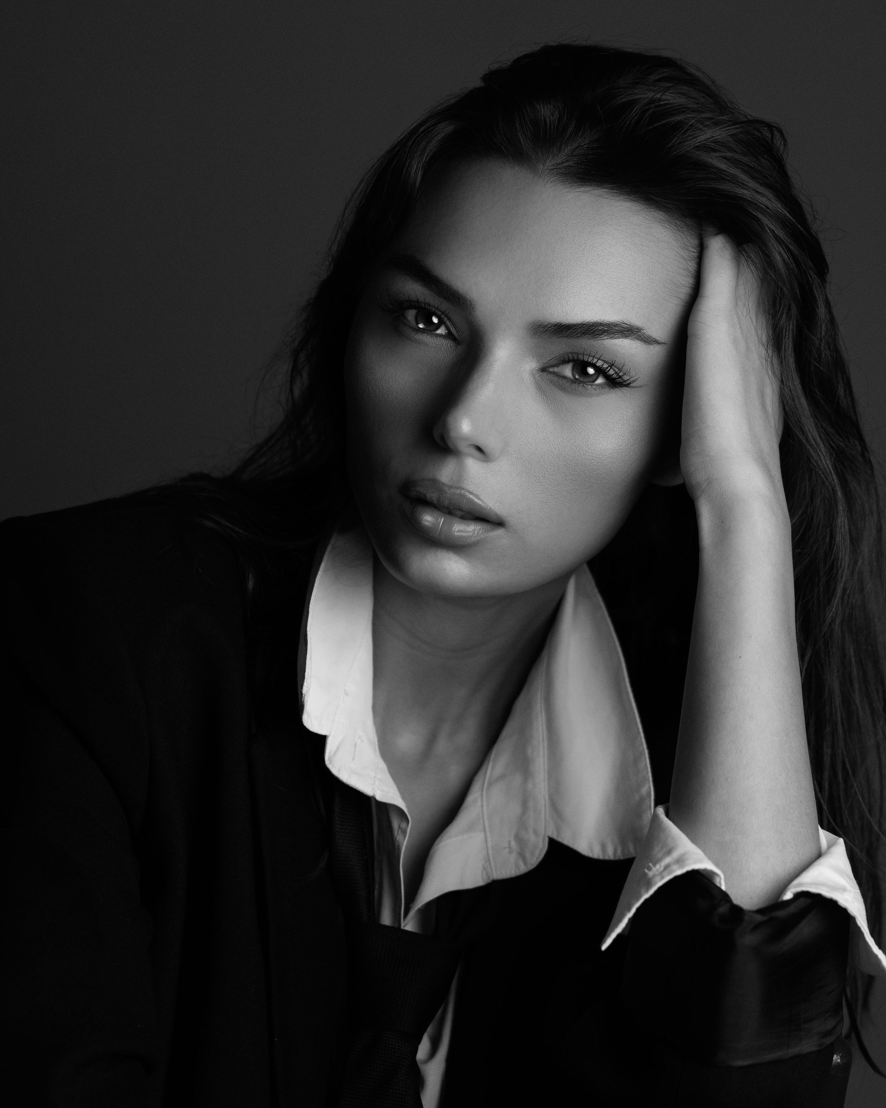 A striking black and white portrait of a woman in formal attire looking contemplative.