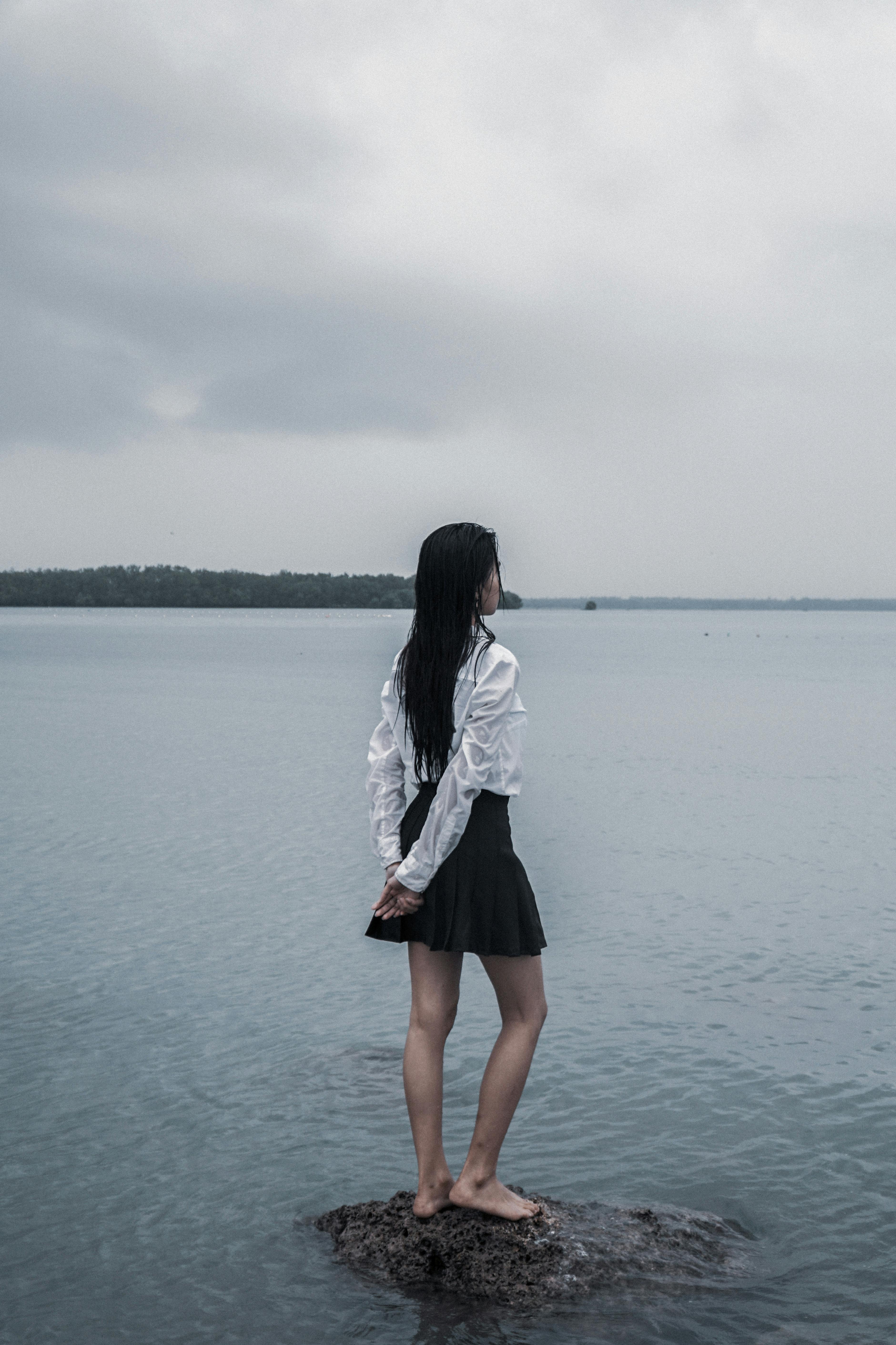 一个女人独自站在海边的岩石上，唤起孤独和内省