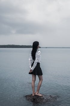 一个女人独自站在海边的岩石上，唤起孤独和内省