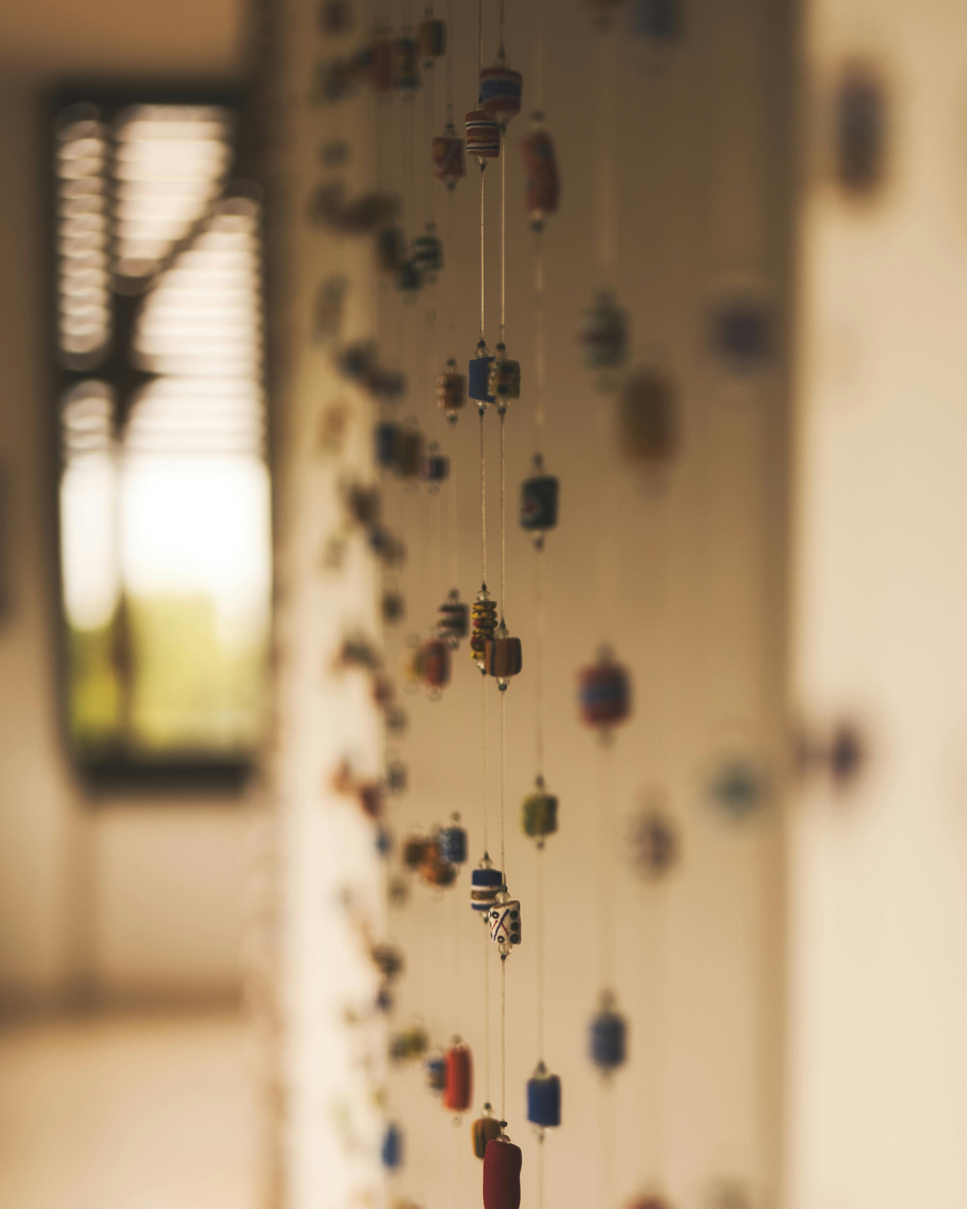 grátis Contas coloridas penduradas em um ambiente interno desfocado, evocando aconchego e expressão artística. Foto profissional