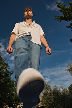 Low angle view of a stylish young man in casual attire outdoors under a clear blue sky in Berlin.