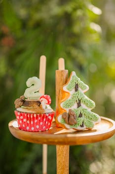 A beautifully decorated cupcake and Christmas tree cookie on a wooden stand, perfect for the holiday season.