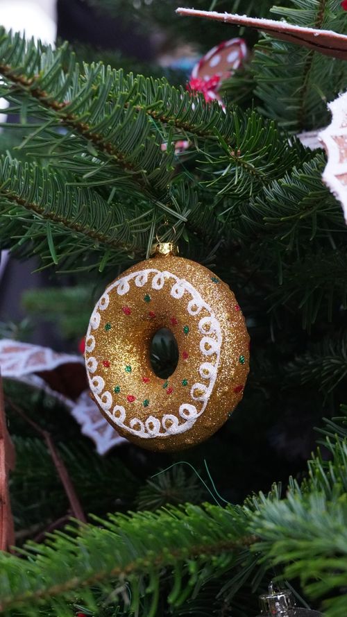 Free Close-up of a gold donut ornament with intricate details hanging on a Christmas tree. Stock Photo
