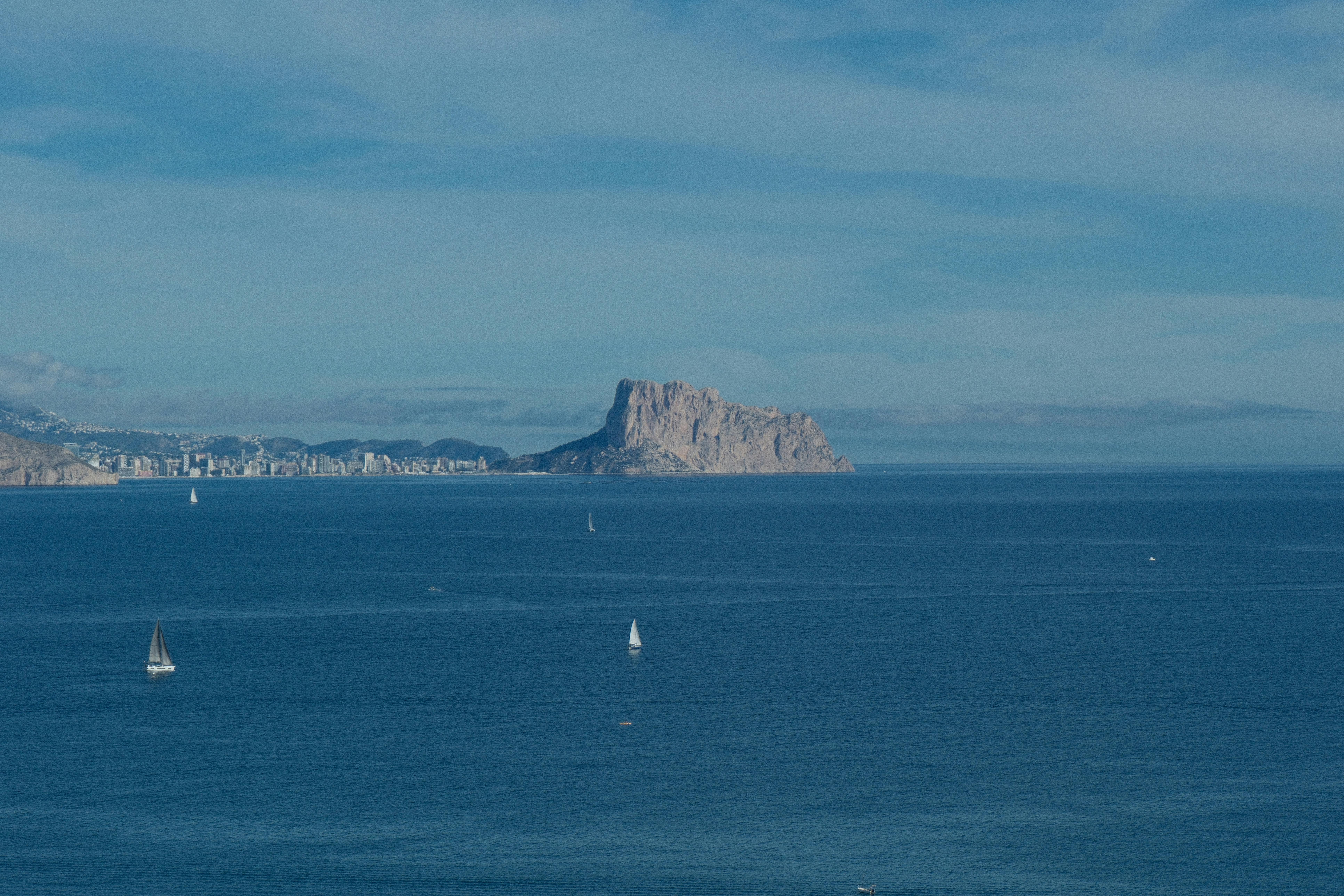 Beautiful view of Peñón de Ifach and sailboats in the clear Mediterranean Sea near El Albir, Spain.