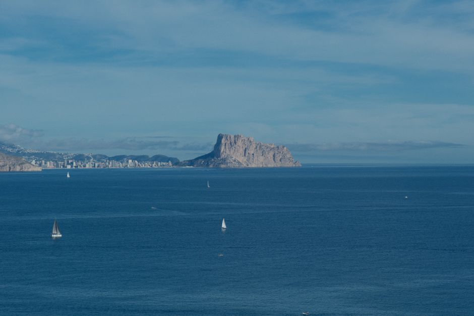Beautiful view of Peñón de Ifach and sailboats in the clear Mediterranean Sea near El Albir, Spain.
