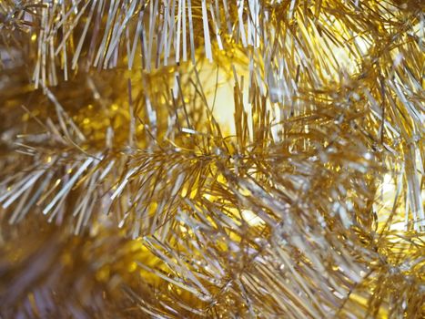 Festive close-up of gold tinsel with bright lighting, perfect for holiday decoration themes.