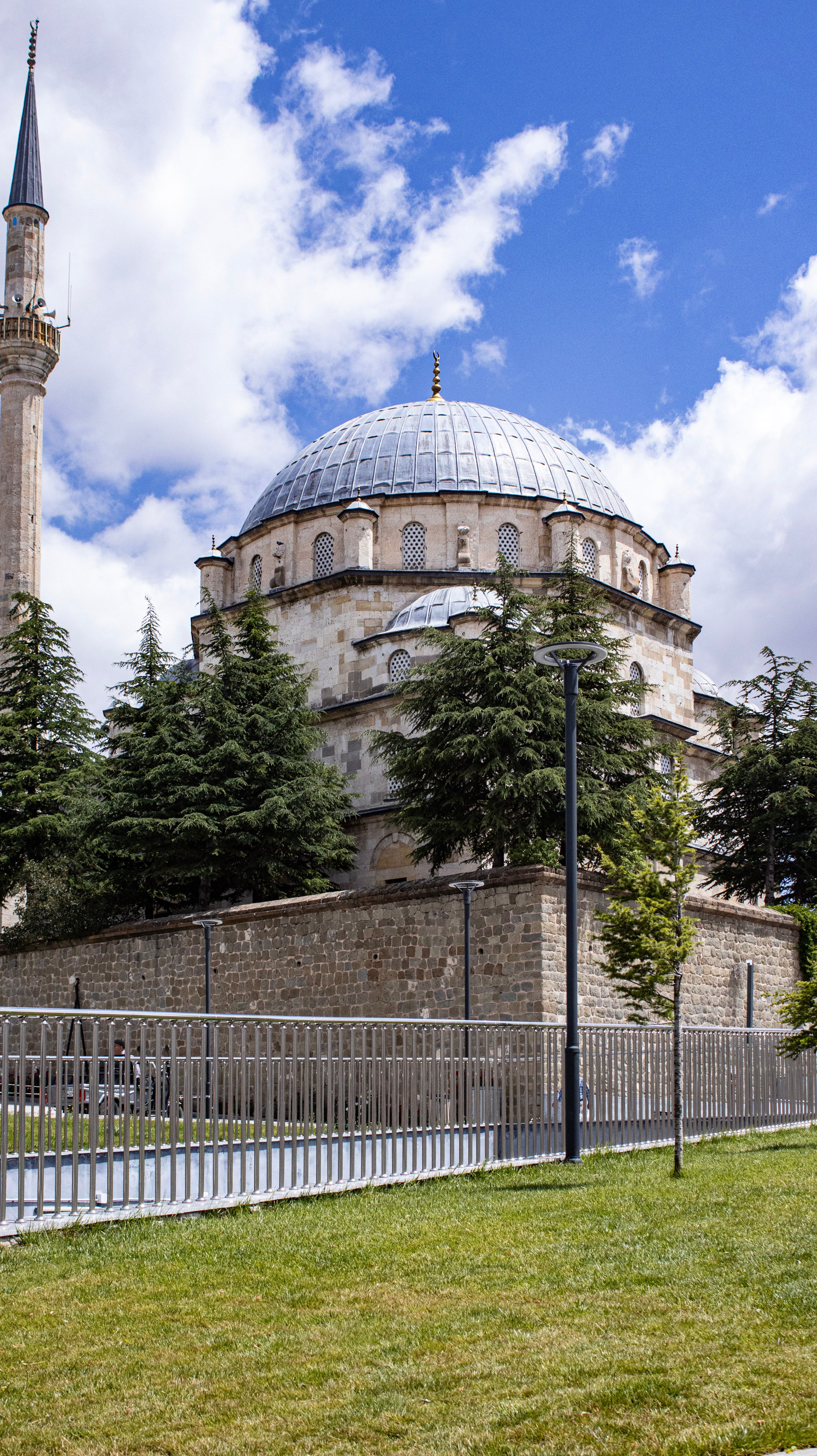 A beautiful view of a historical mosque with a dome and minaret in Yozgat, surrounded by trees and clear skies.