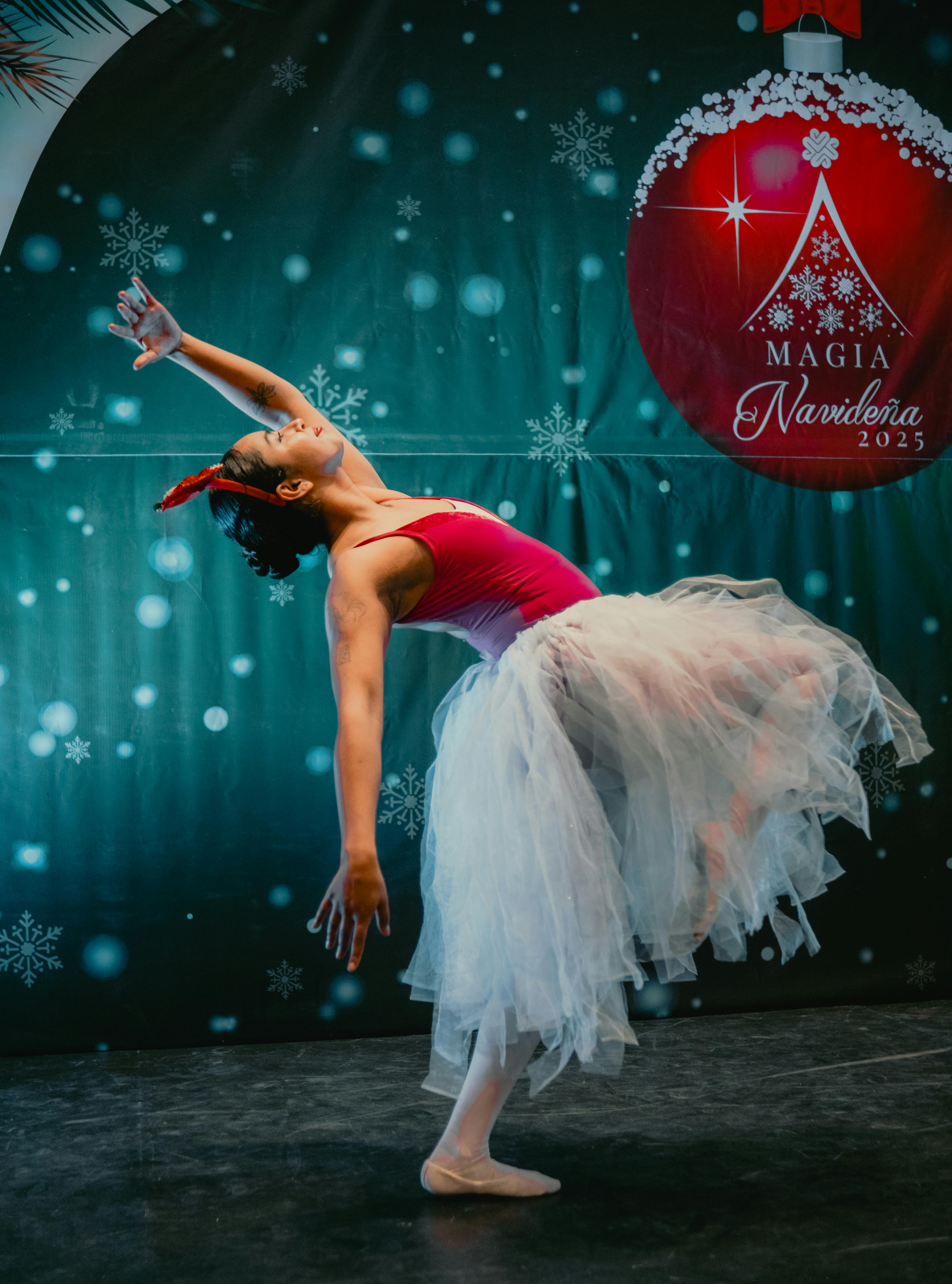 Kostenlos Elegante Ballerina tanzt bei einer festlichen Weihnachtsveranstaltung vor einer Kulisse aus Schneeflocken. Stock-Foto