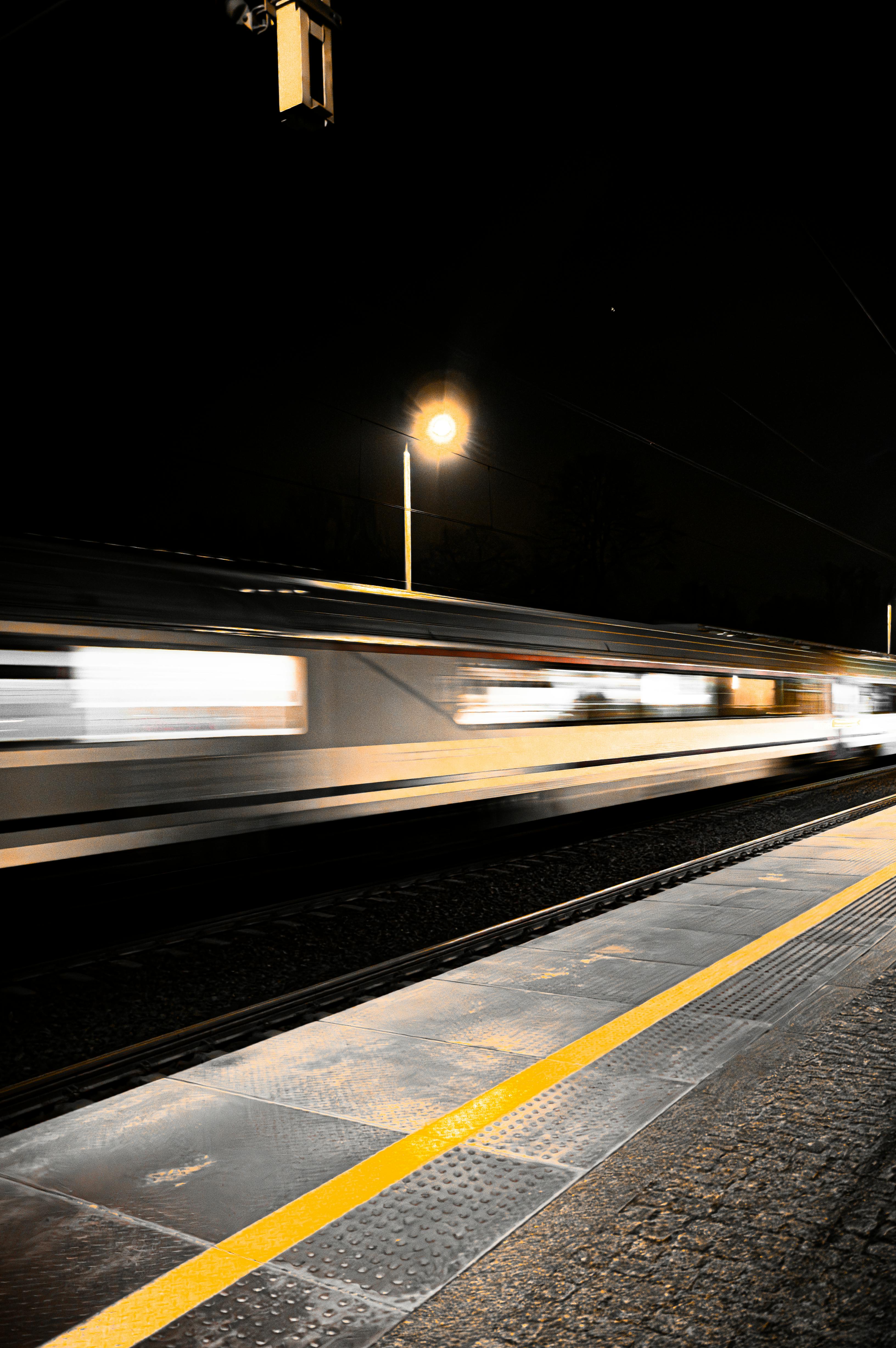 Long exposure shot of a train speeding through a station at night, capturing motion blur.