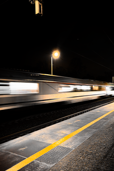 Long exposure shot of a train speeding through a station at night, capturing motion blur.