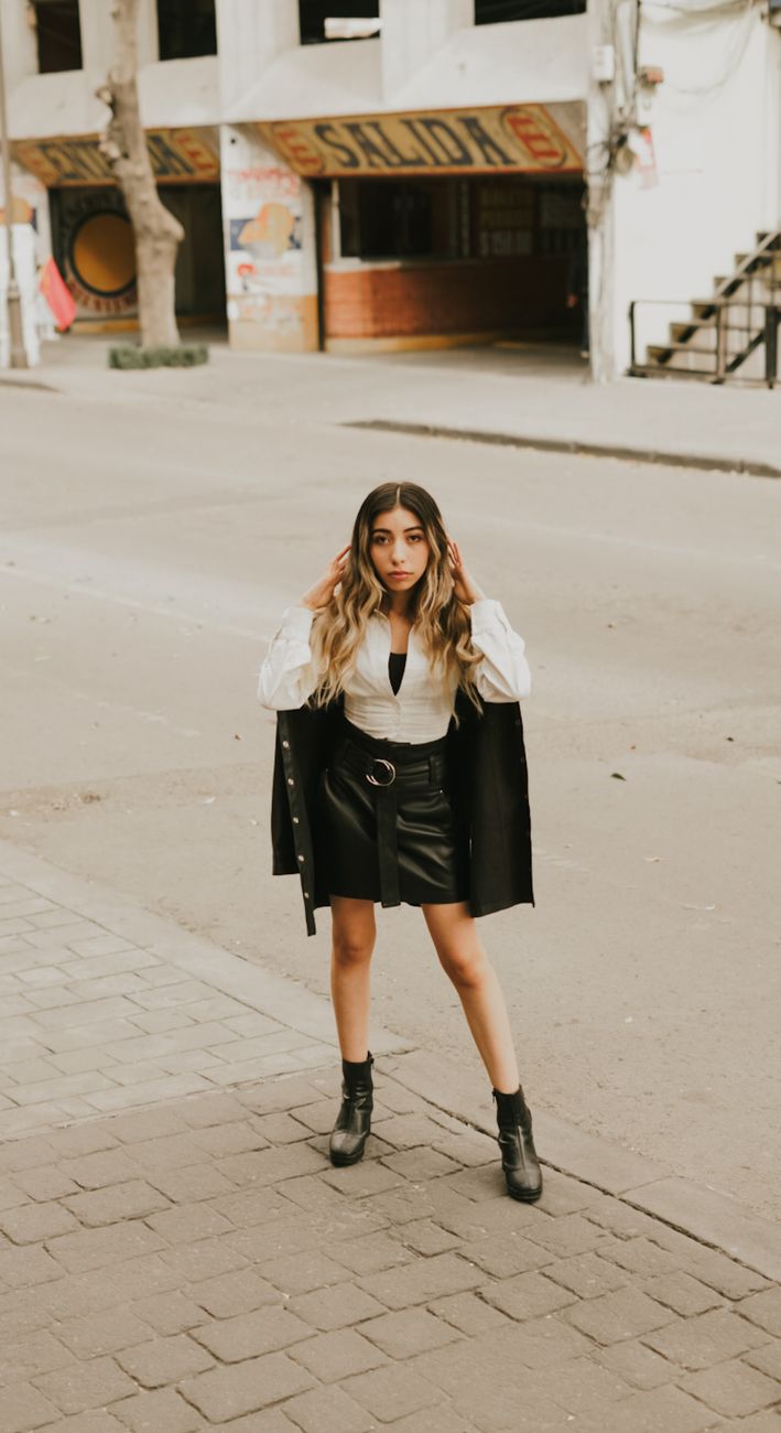Stylish young woman poses confidently on a city street in a fashionable black outfit.