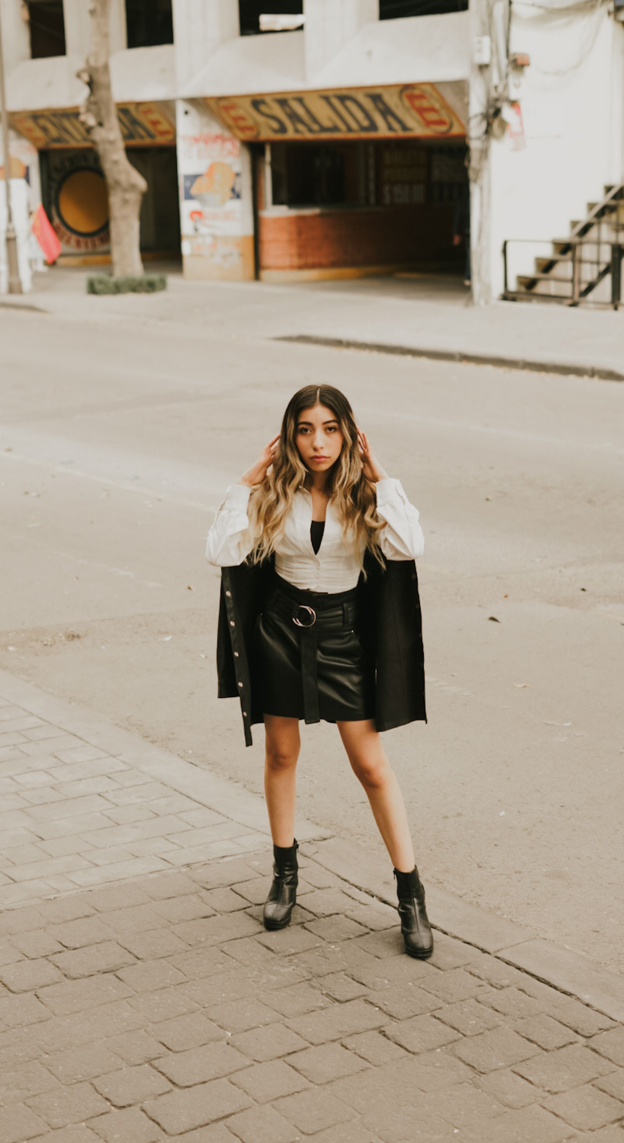 Uma jovem elegante posa com confiança em uma rua da cidade, vestindo um look preto da moda.