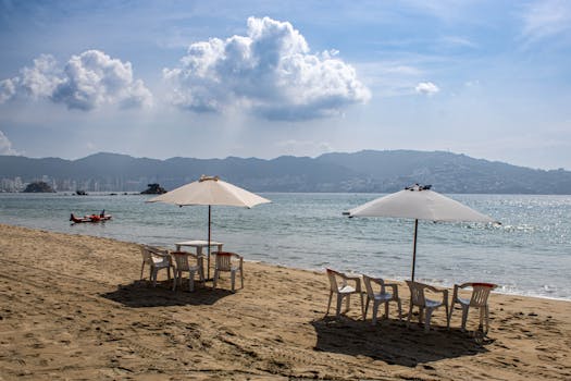 A peaceful beach scene in Acapulco with umbrellas and chairs overlooking the sea on a sunny day.