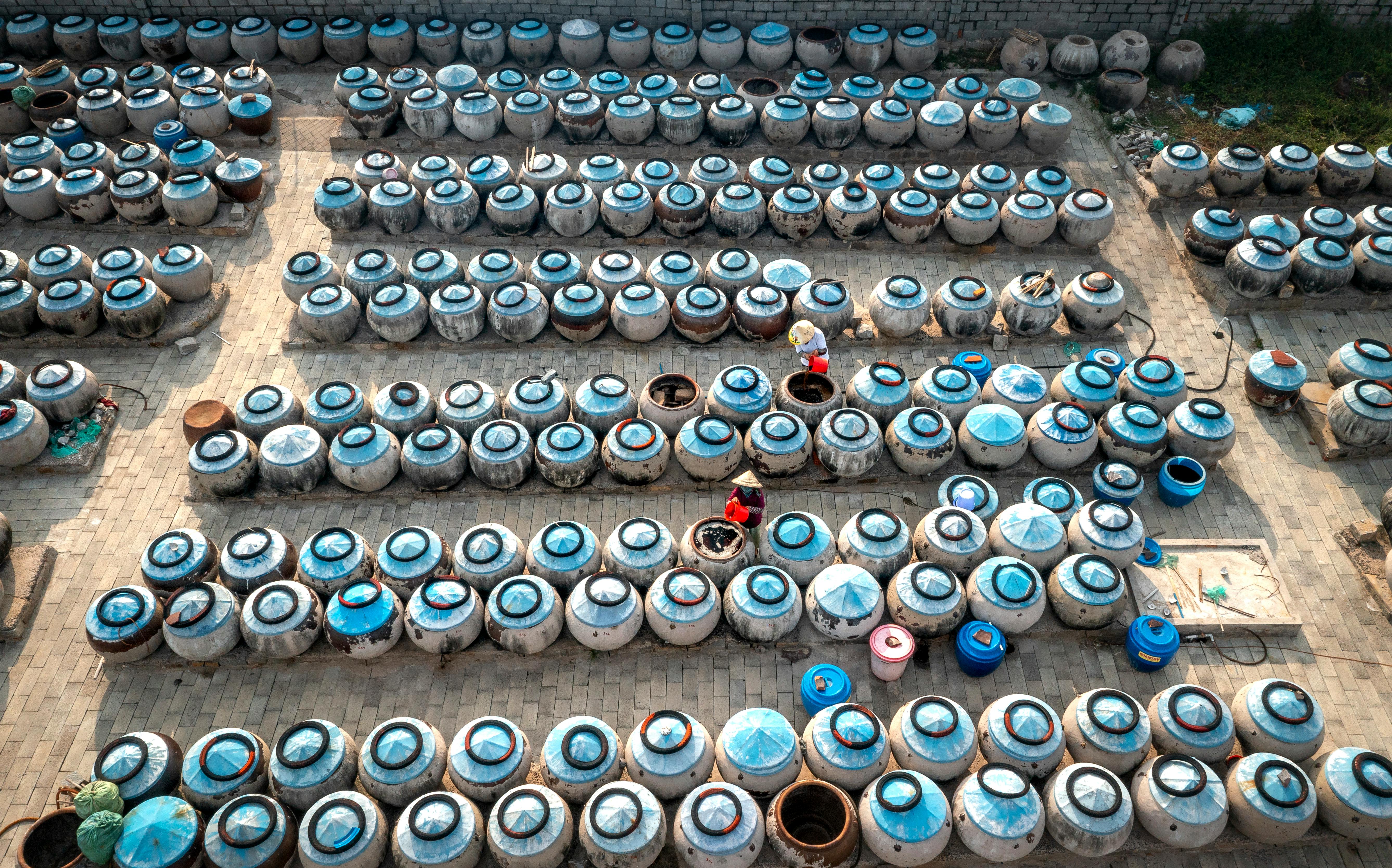 Free Rows of fish sauce jars in a Vietnamese courtyard, showcasing traditional fermentation and local culture. Stock Photo