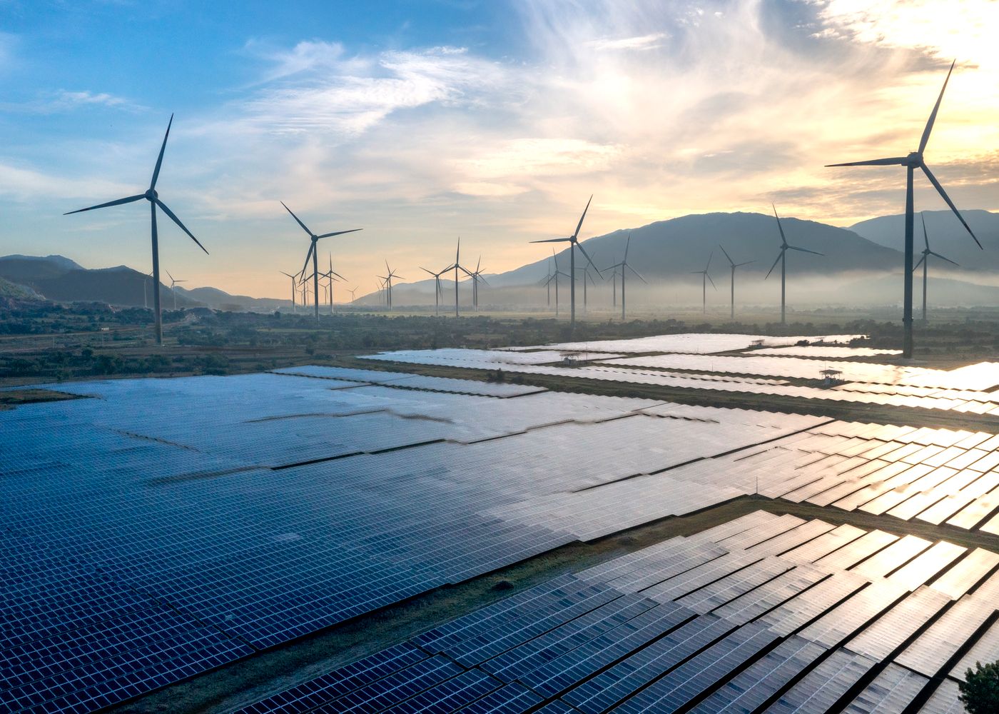 Solar panels and wind turbines at sunset, representing clean renewable energy