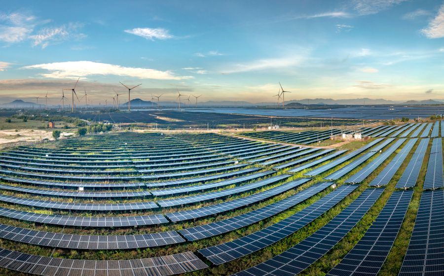 Vaste ferme solaire avec éoliennes à l'horizon