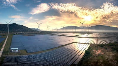 Aerial view of solar panels and wind turbines at sunrise