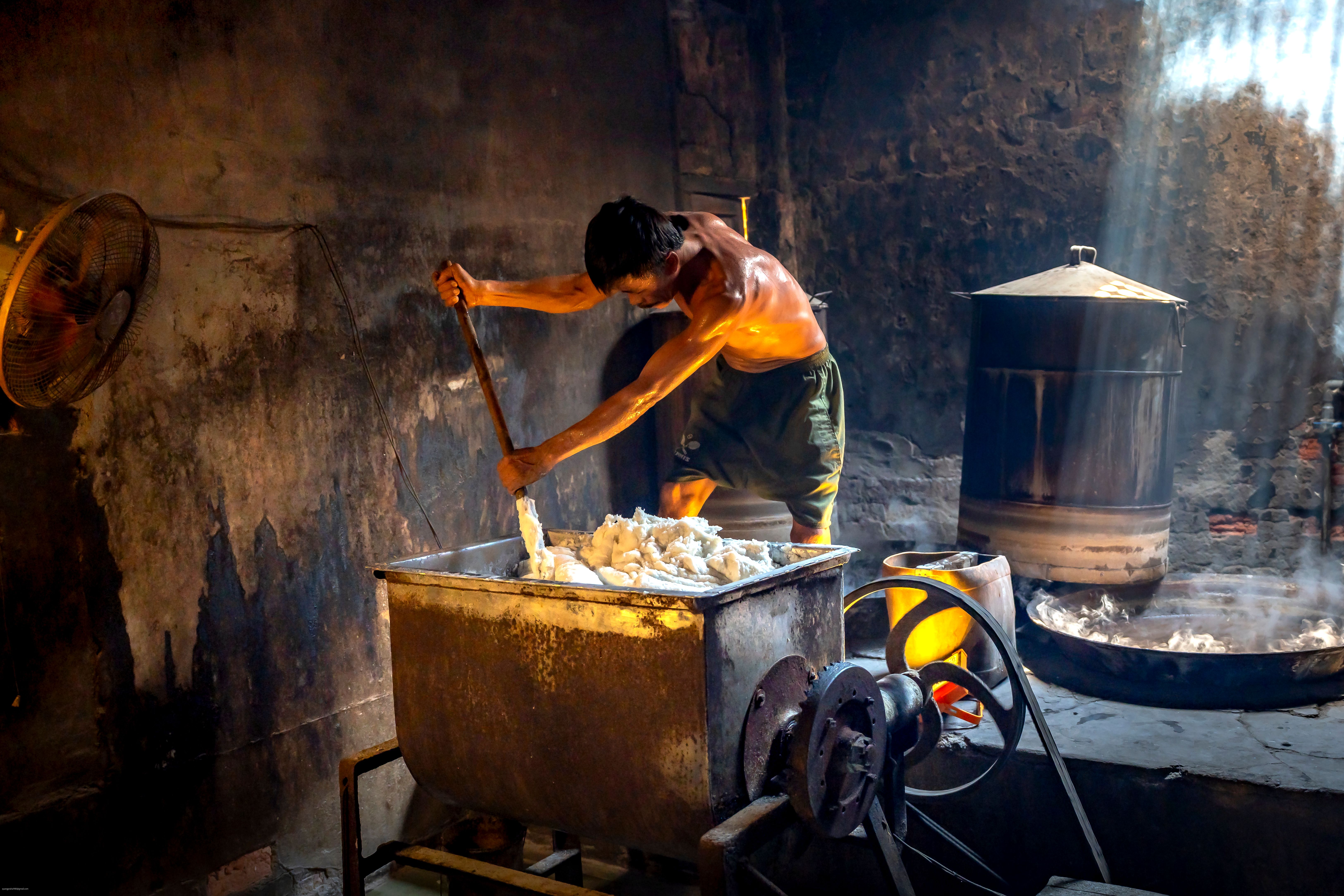 Man stirring a vat in an industrial soap factory, illuminated by natural light — what is small scale industries