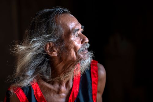 Free Portrait of an elderly man with long hair, wearing a traditional outfit, gazing thoughtfully. Stock Photo