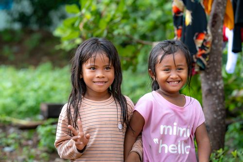 Free Two happy children outside, smiling and enjoying a sunny day, surrounded by lush greenery. Stock Photo