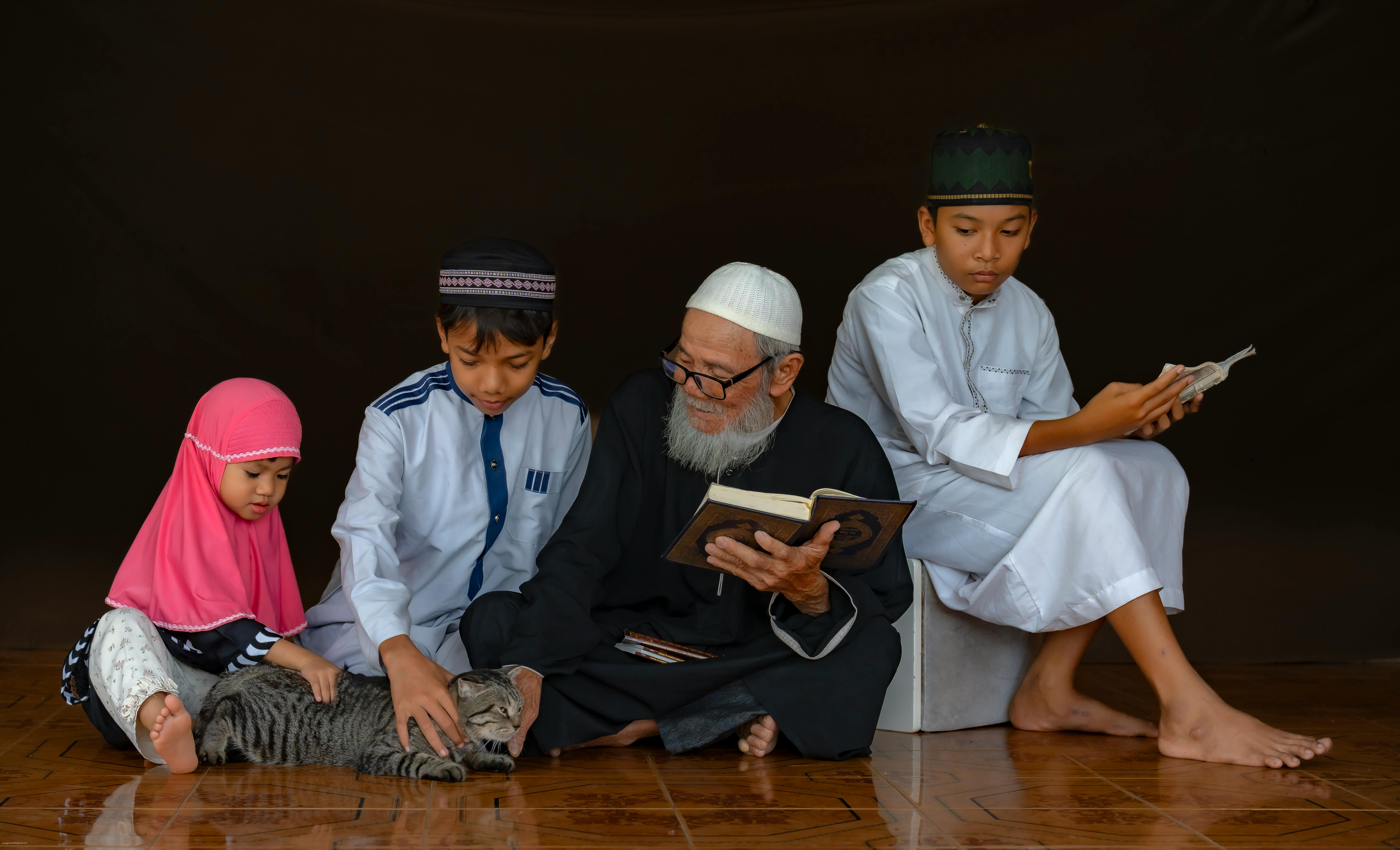 A multigenerational family reading religious texts while bonding with a pet cat.