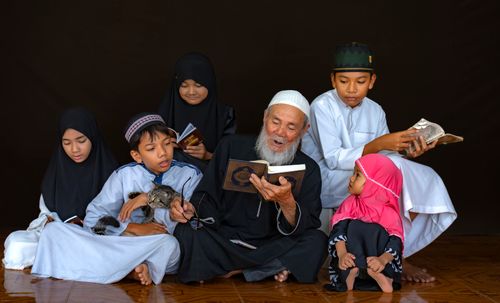 Free A multigenerational family reading the Quran together, emphasizing togetherness and faith. Stock Photo