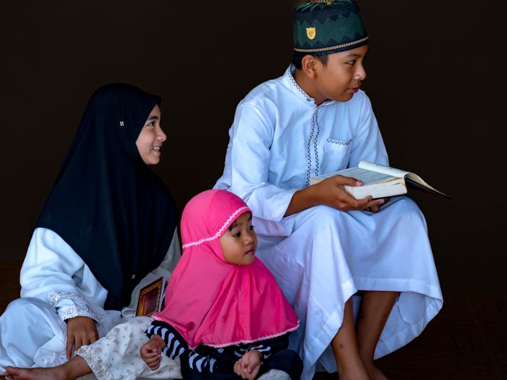 Three Muslim children reading the Quran together