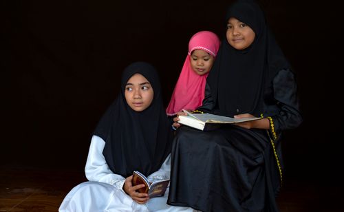 Free Three girls in hijabs reading books, symbolizing education and cultural heritage. Stock Photo
