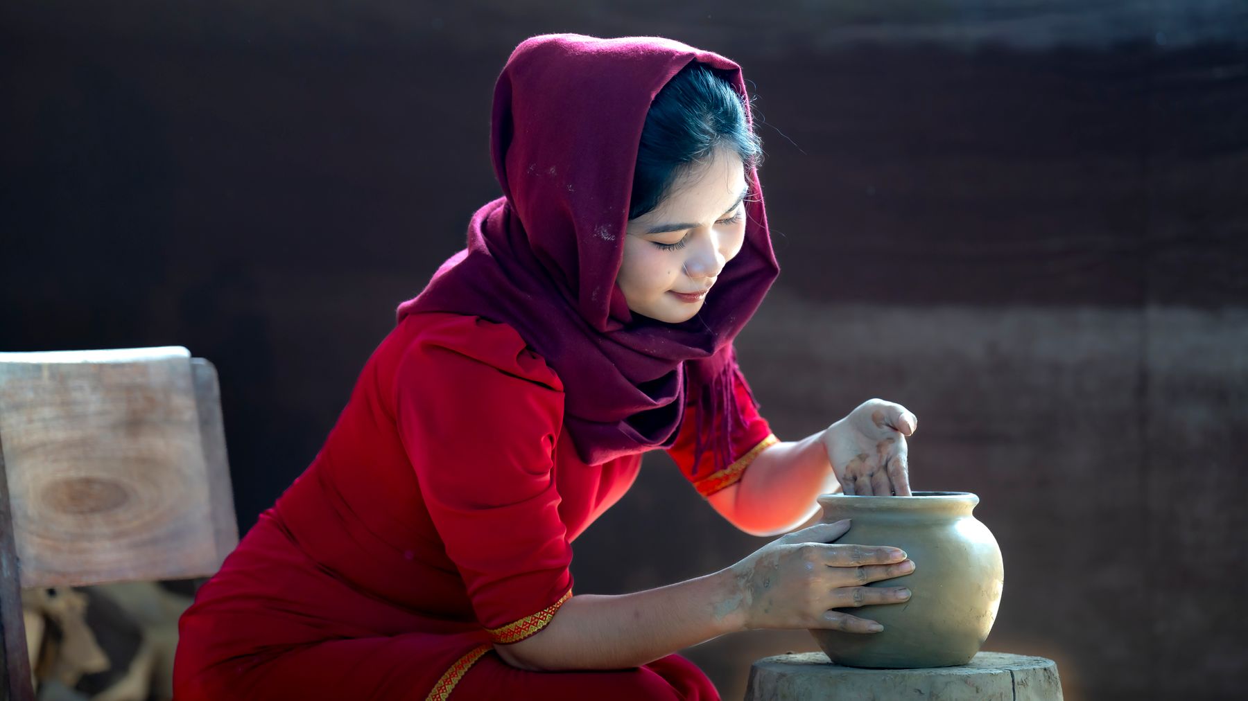 Young woman in traditional attire skillfully crafting pottery, showcasing cultural artistry.