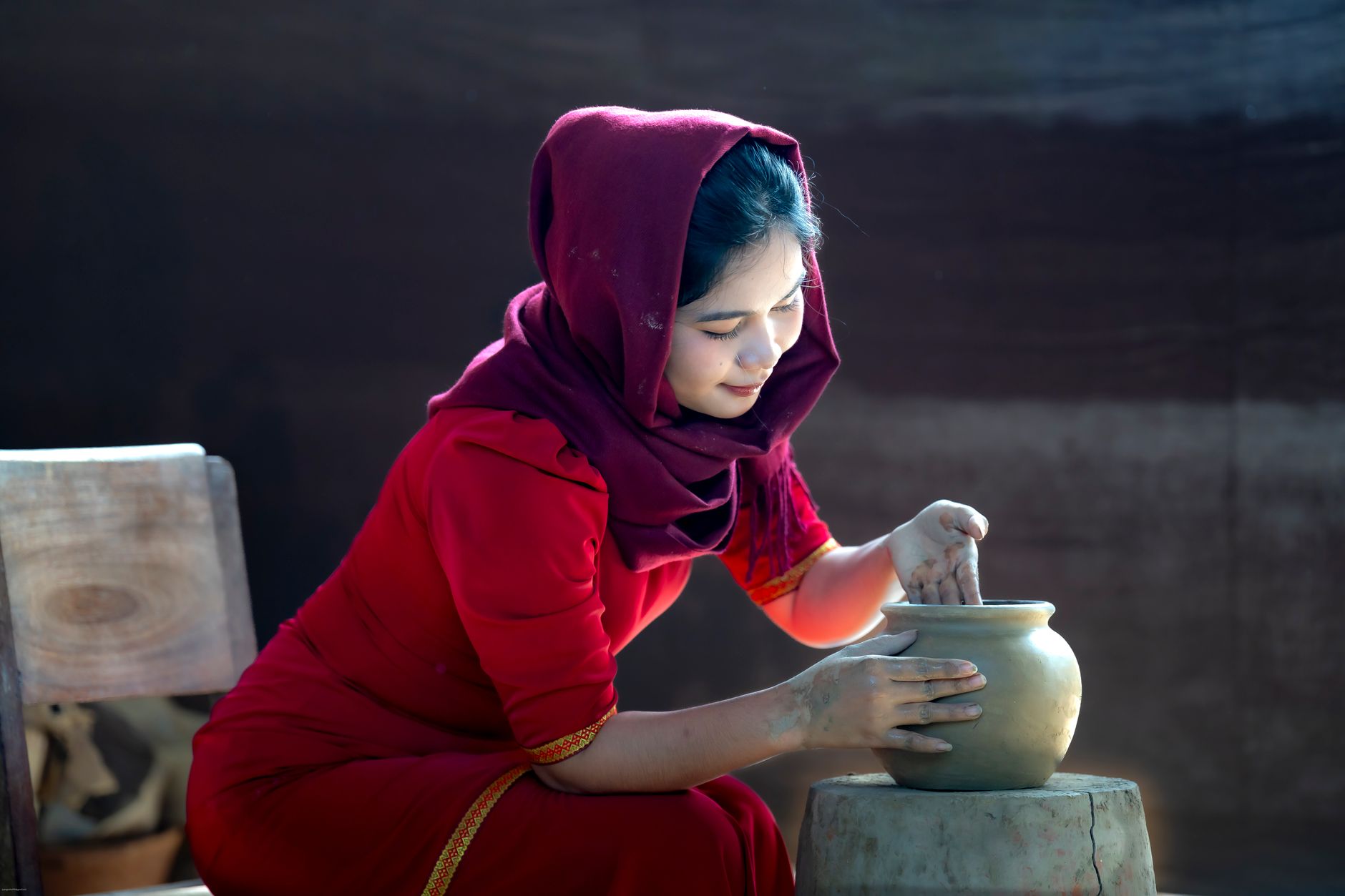 Young woman in traditional attire skillfully crafting pottery, showcasing cultural artistry.