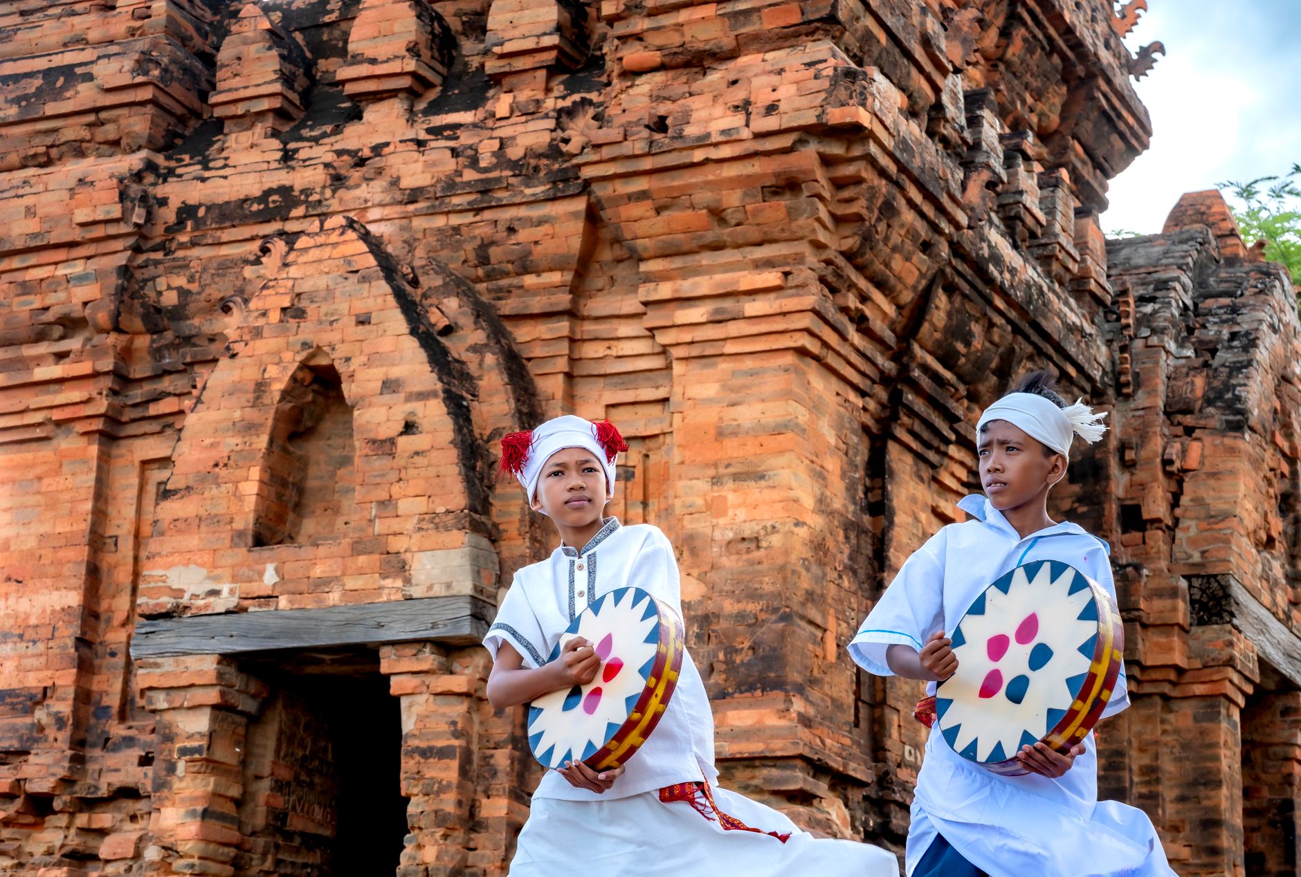 Two young performers in traditional attire performing a cultural dance at Po Klong Garai Temple in Vietnam.