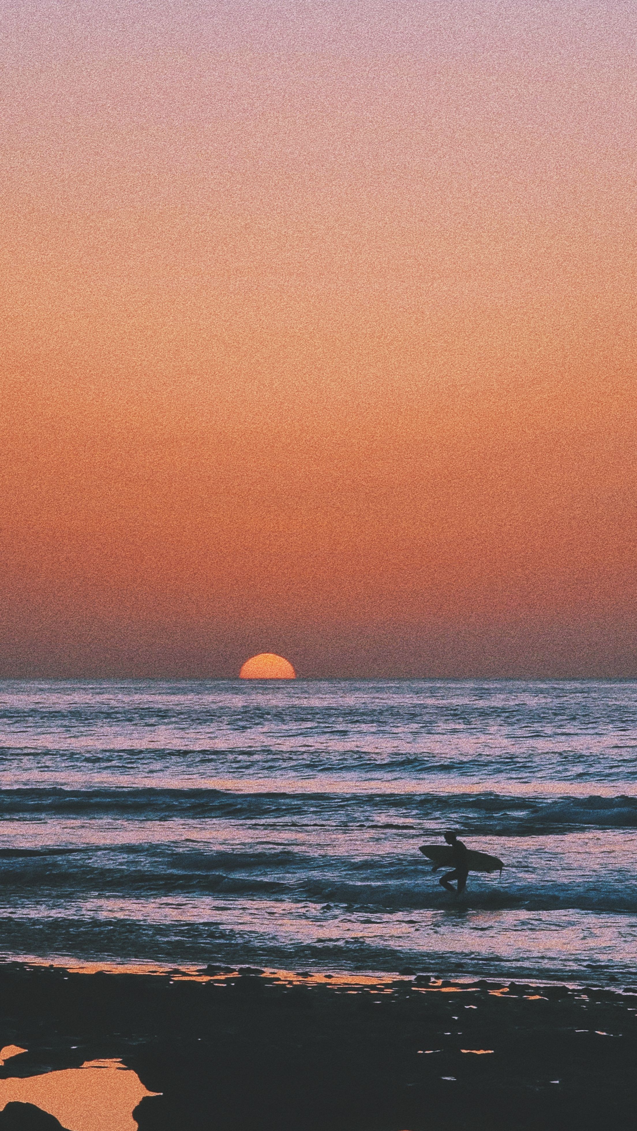 A surfer during a vibrant sunset over the ocean, capturing the essence of adventure and tranquility.