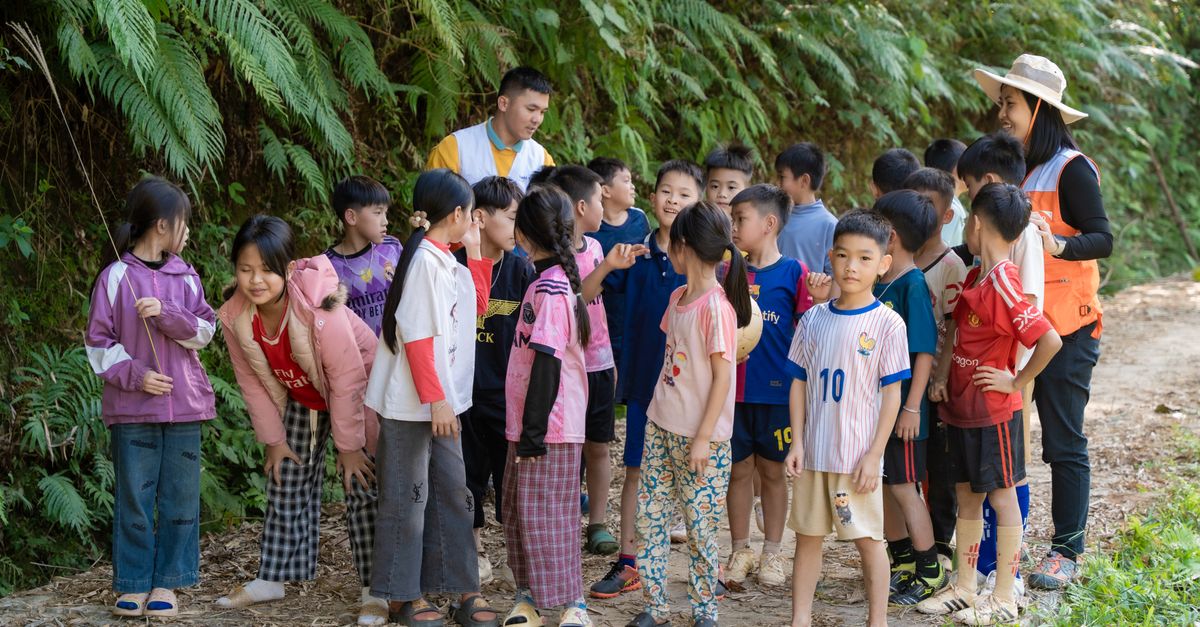 Group of children engaged in outdoor learning activity on a nature trail with two adult guides.